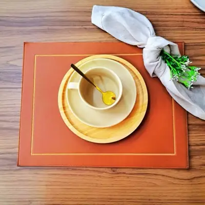Jogo americano retangular terracota com friso de moldura em relevo, xícara de café e guardanapo